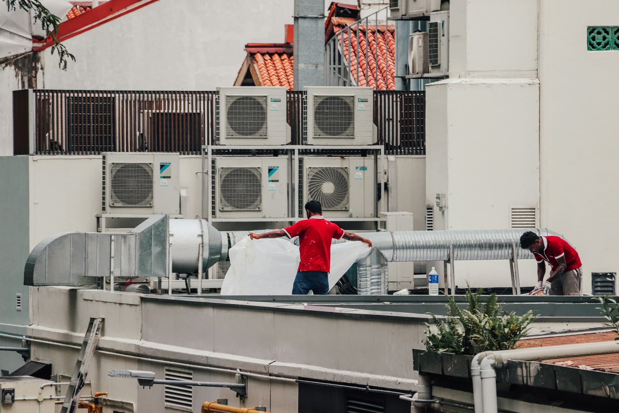 HVAC technicians installing ductwork beside rooftop air conditioning units